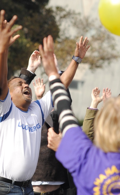 A group of people participating in a Laughter Yoga event with their hands in the air